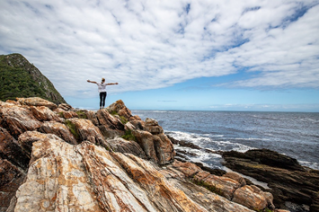 Mit offenen Armen auf einem Felsen am Meer